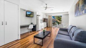 A modern living room with a grey sofa, a black coffee table, and a TV mounted on the wall. - Essence Apartments Chermside (Chermside)