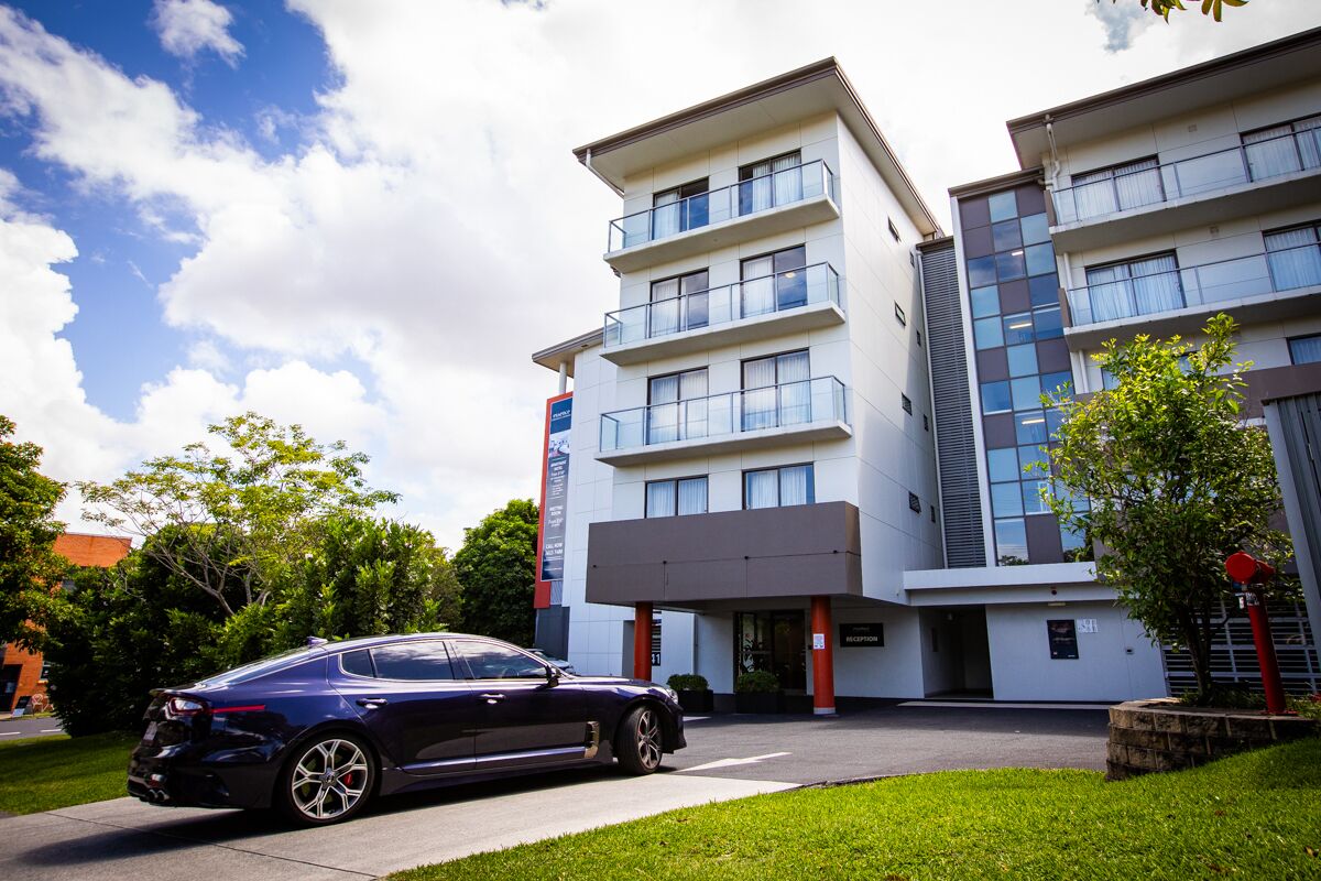 A modern hotel with a reception area, multiple floors, and a parked car in front.