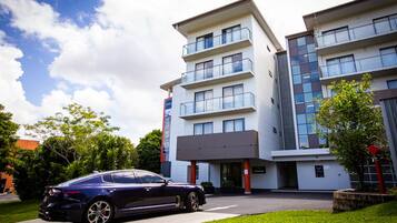 A modern hotel with a reception area, multiple floors, and a parked car in front.