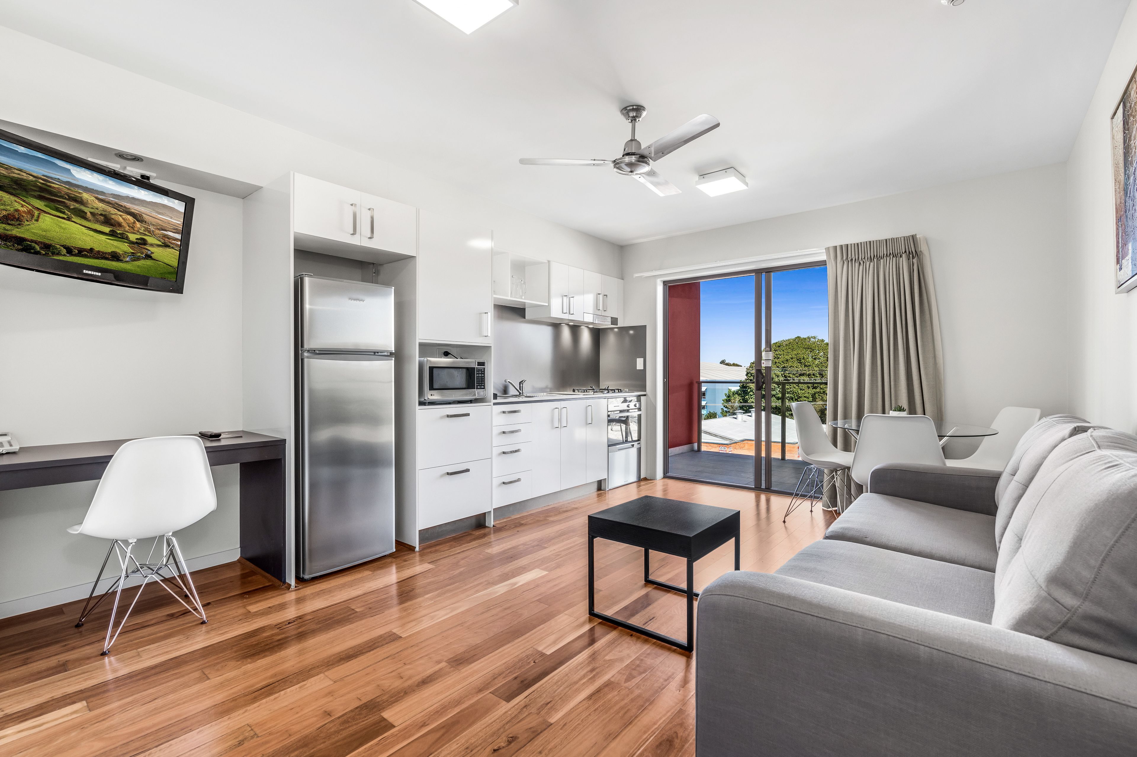 A modern kitchen with a built-in microwave, stainless steel refrigerator, and white cabinets.