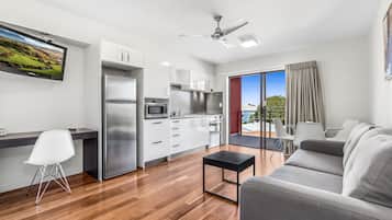 A modern kitchen with a built-in microwave, stainless steel refrigerator, and white cabinets.