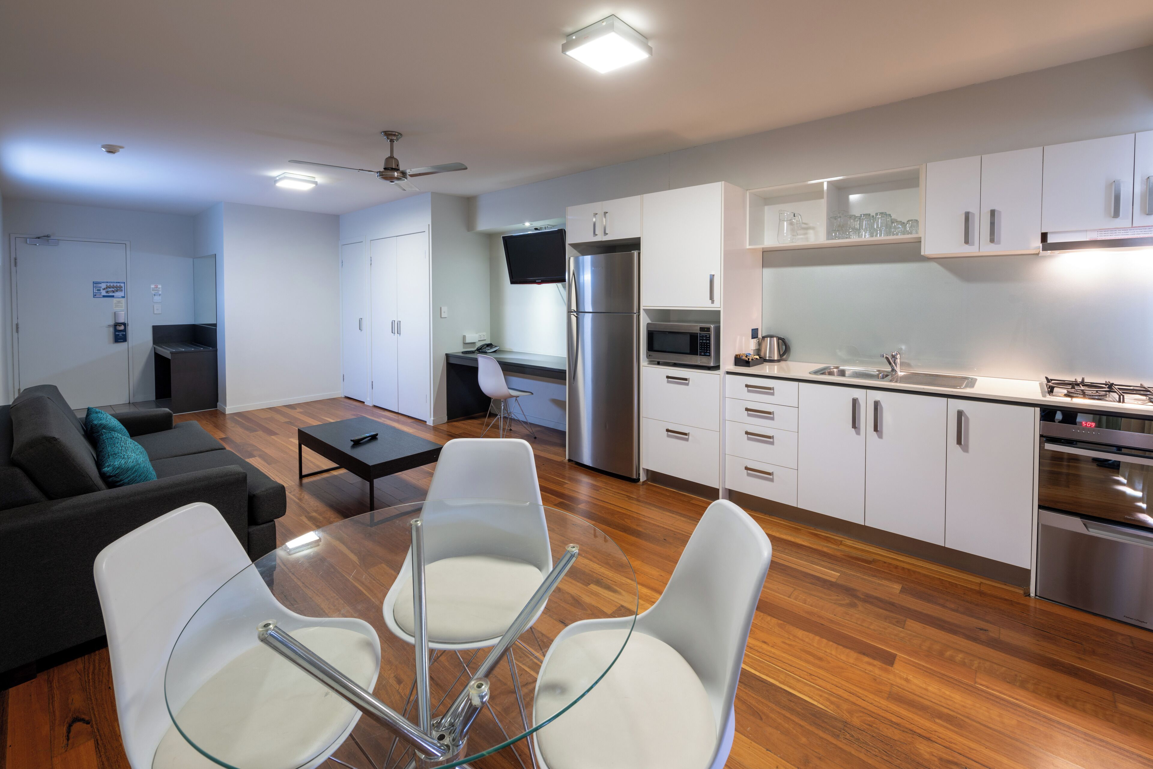 A modern kitchen with white cabinets, stainless steel appliances, and a dining area with glass chairs and a table.