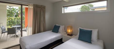 A hotel room with two beds, a ceiling fan, a window, and a balcony with outdoor seating.
