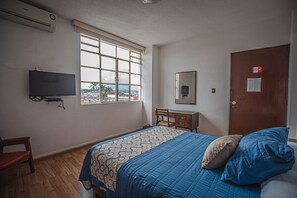 A bedroom with a bed, a chair, a desk, a television, and a window with a view. - Hotel Palacio (Córdoba)