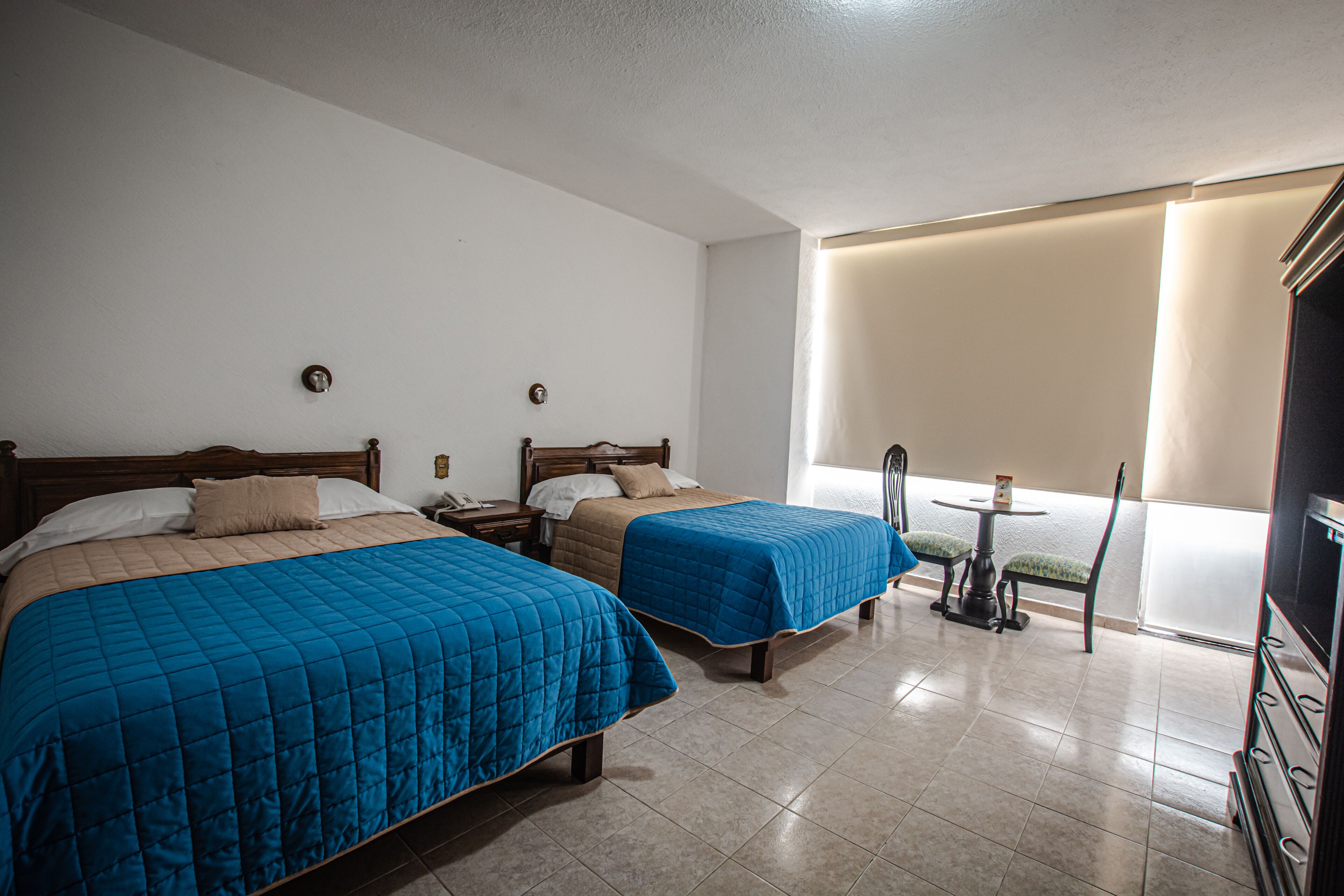 A hotel room with two beds, a small table, and a TV.