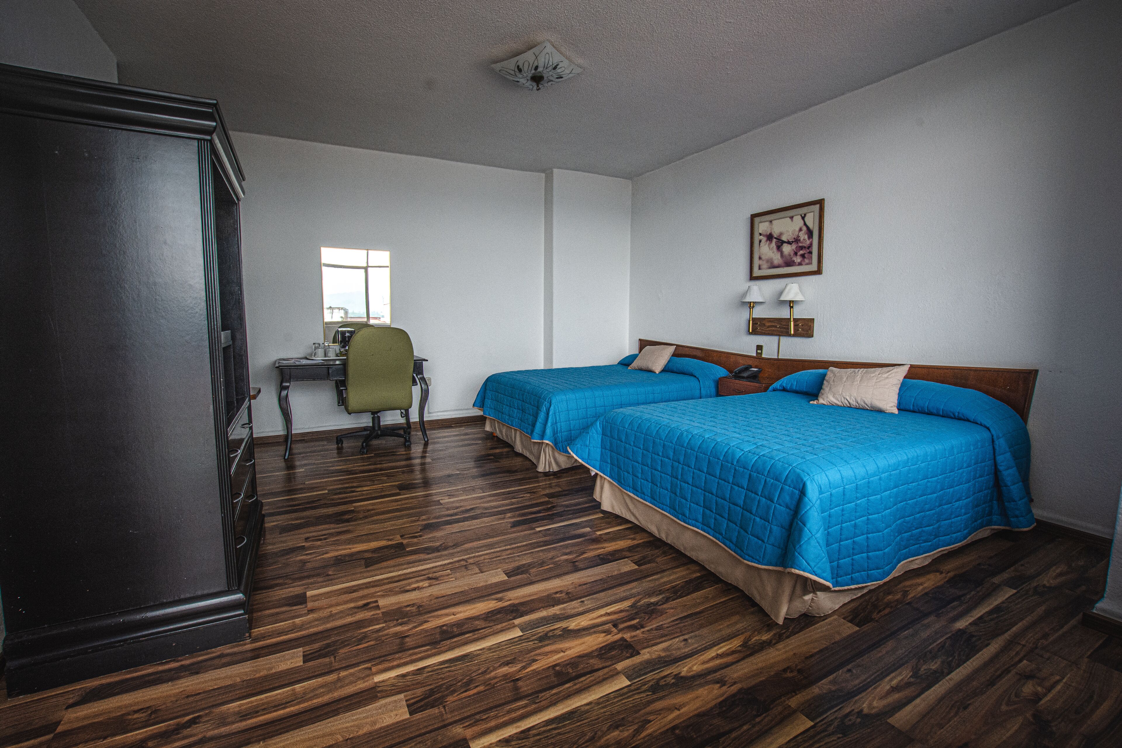 Habitación de hotel con dos camas, un escritorio y una silla.