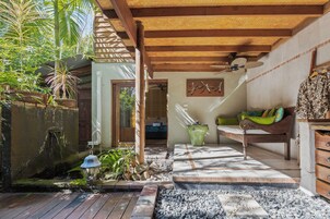 Una terraza de madera con un camino de piedra que lleva a un banco de madera y una maceta verde.