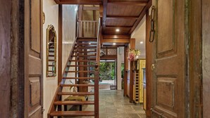 A wooden staircase leading to an upper level, flanked by wooden doors and a stone floor. - The Garden Burees (Byron Bay)