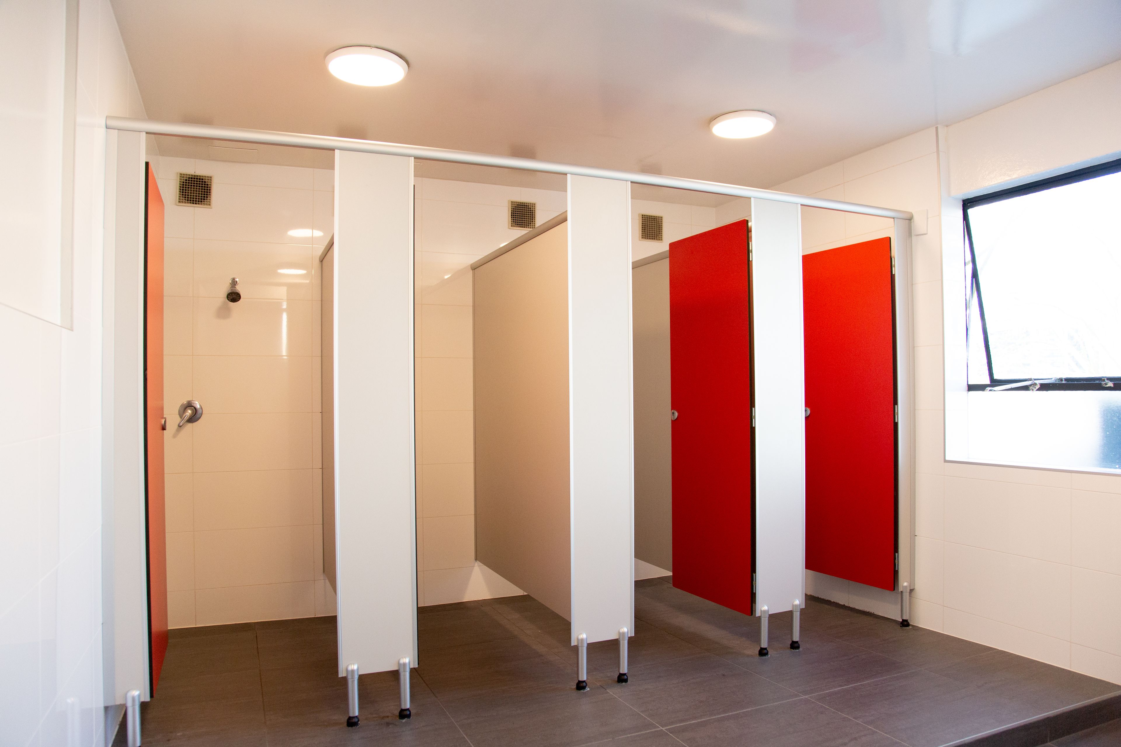 Un baño moderno con mampara de vidrio, ducha y puerta roja.