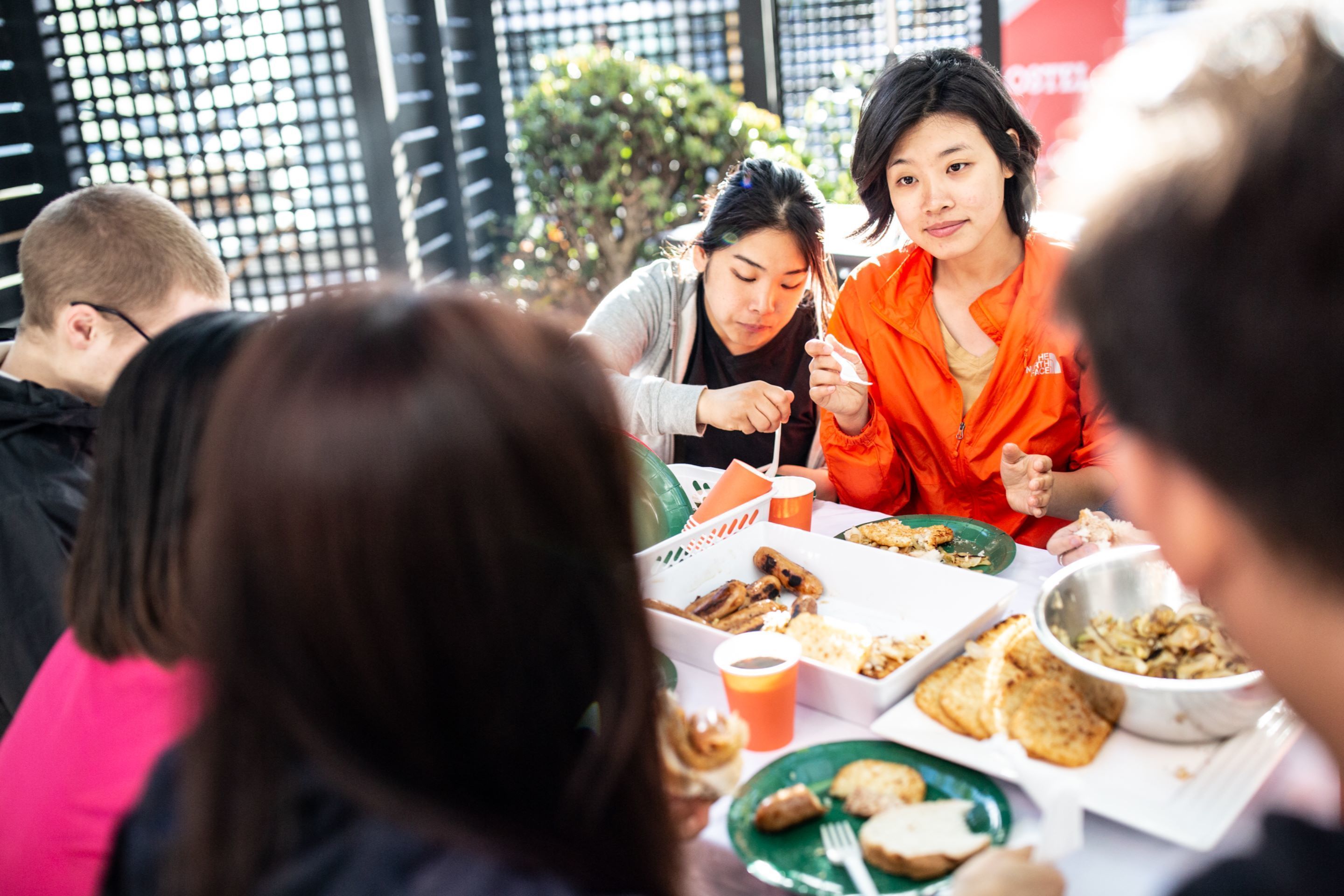 A group of people dining at a table with various dishes and drinks.
