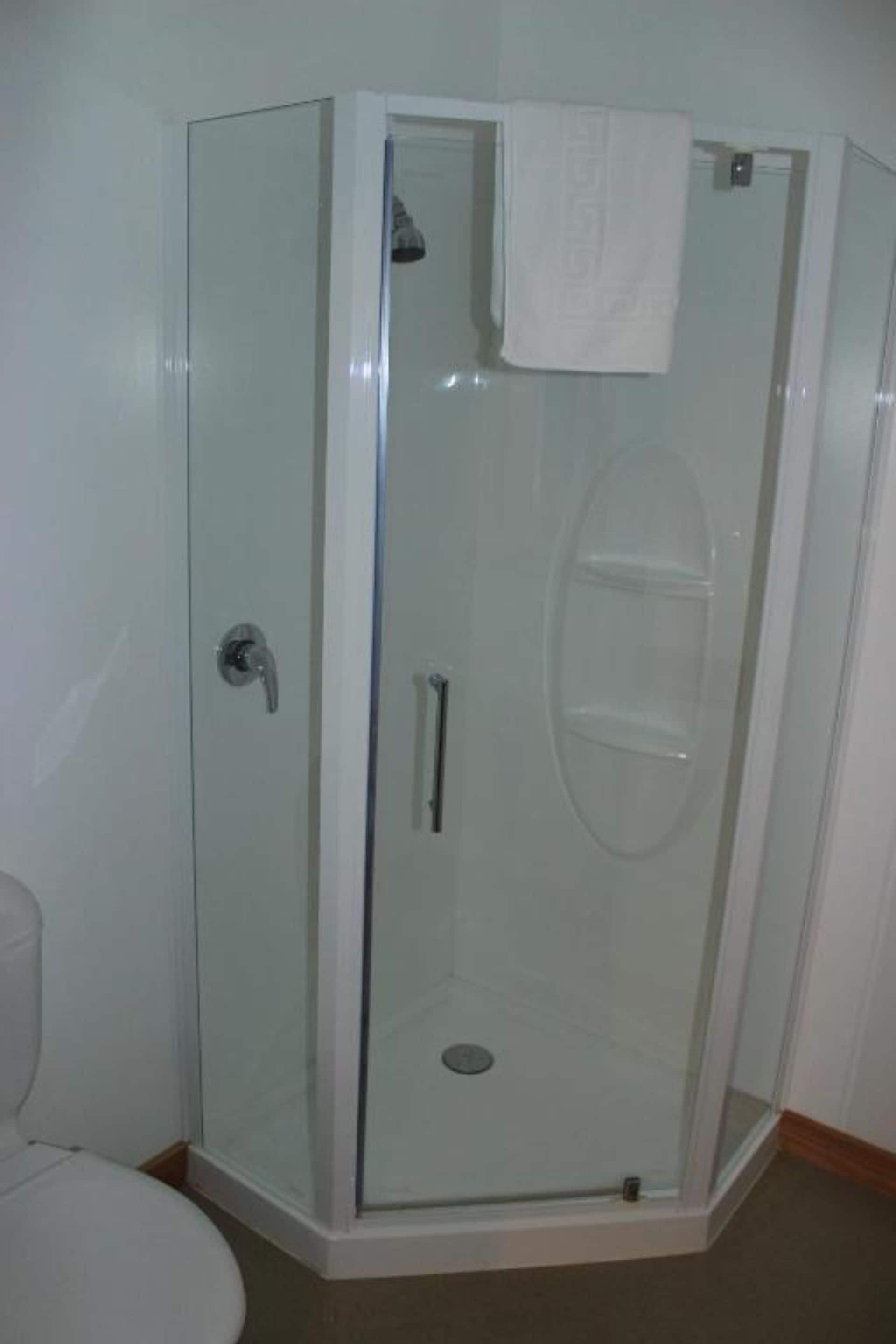 Een douche met glazen wanden en een witte handdoek aan de deur.