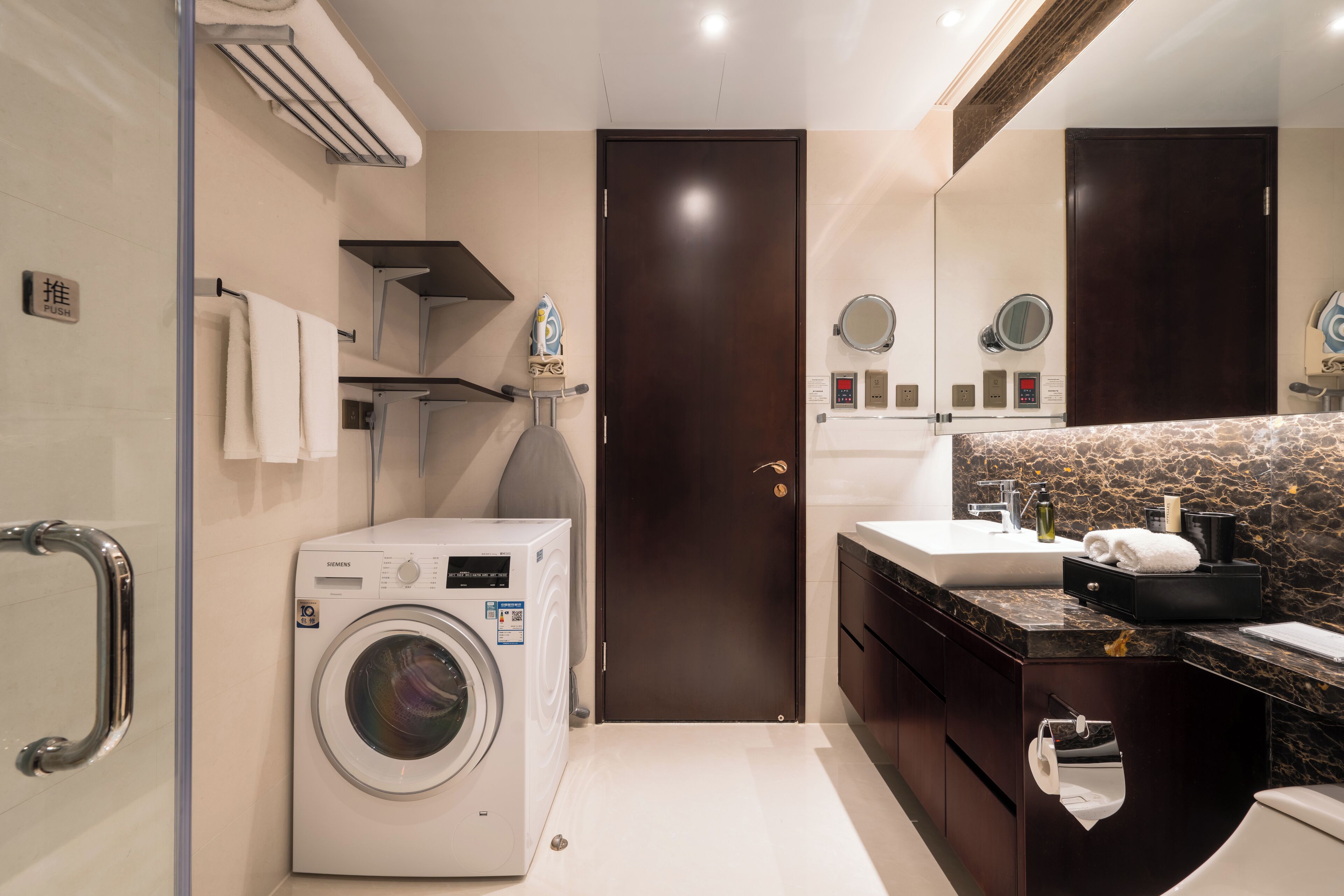A modern bathroom with a washing machine, a sink, and a mirror.