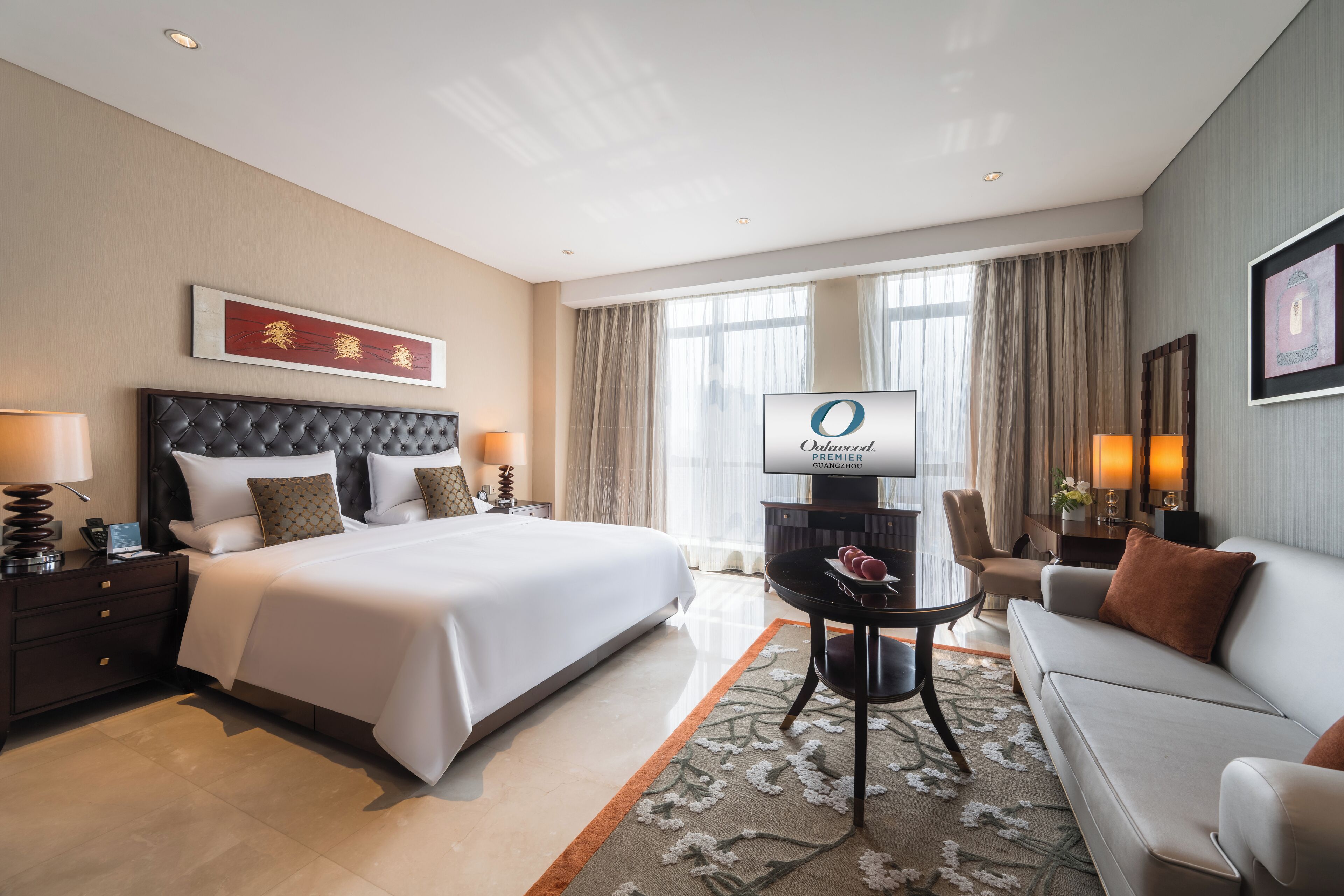 A hotel room with a large bed, a flat-screen TV, a sofa, and a dining table.