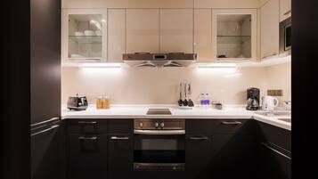 A modern kitchen with dark cabinets, a stainless steel range hood, and a white countertop.