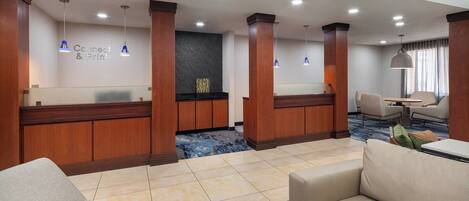 A hotel lobby with a reception desk, seating area, and a dining table.