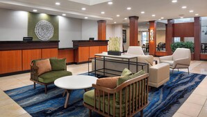 A lobby with a reception desk, seating area, and a large decorative wall piece. - Fairfield Inn & Suites Visalia Tulare (Tulare)
