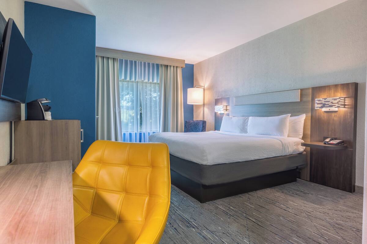 Una habitación de hotel con cama, escritorio, silla y televisión.