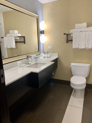 Un baño moderno con un espejo grande, lavamanos dobles, inodoro y toalleros.