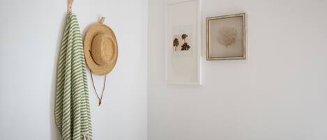 A wall with a straw hat, a striped cloth, and two framed pictures.