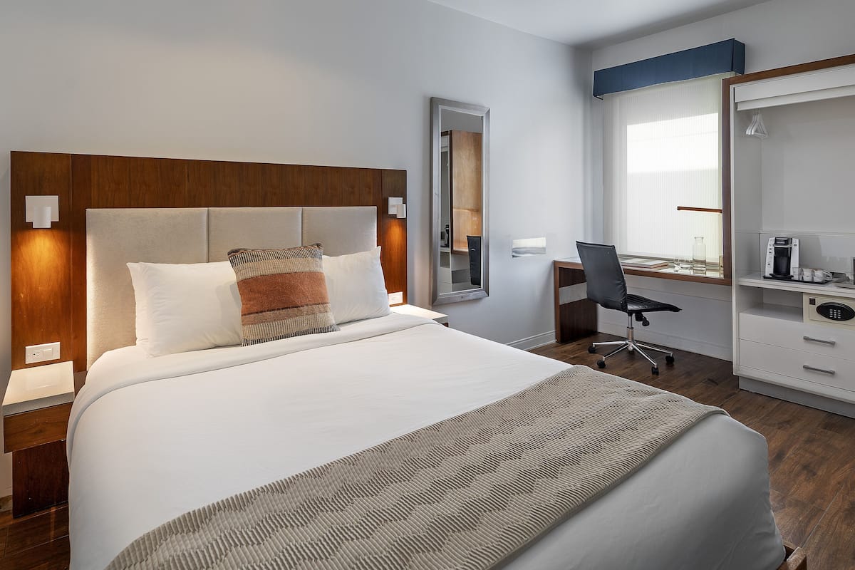 Quarto de hotel moderno com uma cama grande, uma mesa de trabalho e um guarda-roupa.