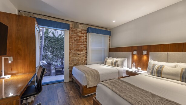 A hotel room with two beds, a desk, and a view of the outdoors. - Riviera Beach House (Santa Barbara)