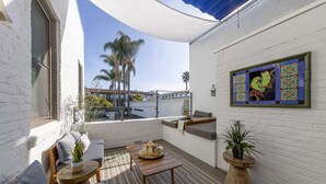 A sunlit patio with a wooden table, seating, and a potted plant. - Riviera Beach House (Santa Barbara)