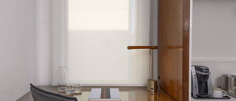 A compact hotel room with a desk, chair, and a wardrobe.