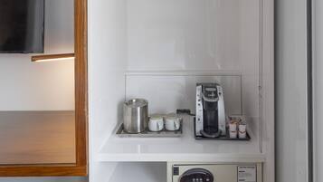 Une petite pièce équipée d’une machine à café intégrée, d’une petite étagère avec des tasses et d’un panneau de commande.