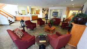 Un hall espacioso con sillones tapizados de rojo, una mesa de centro y un mostrador de recepción.