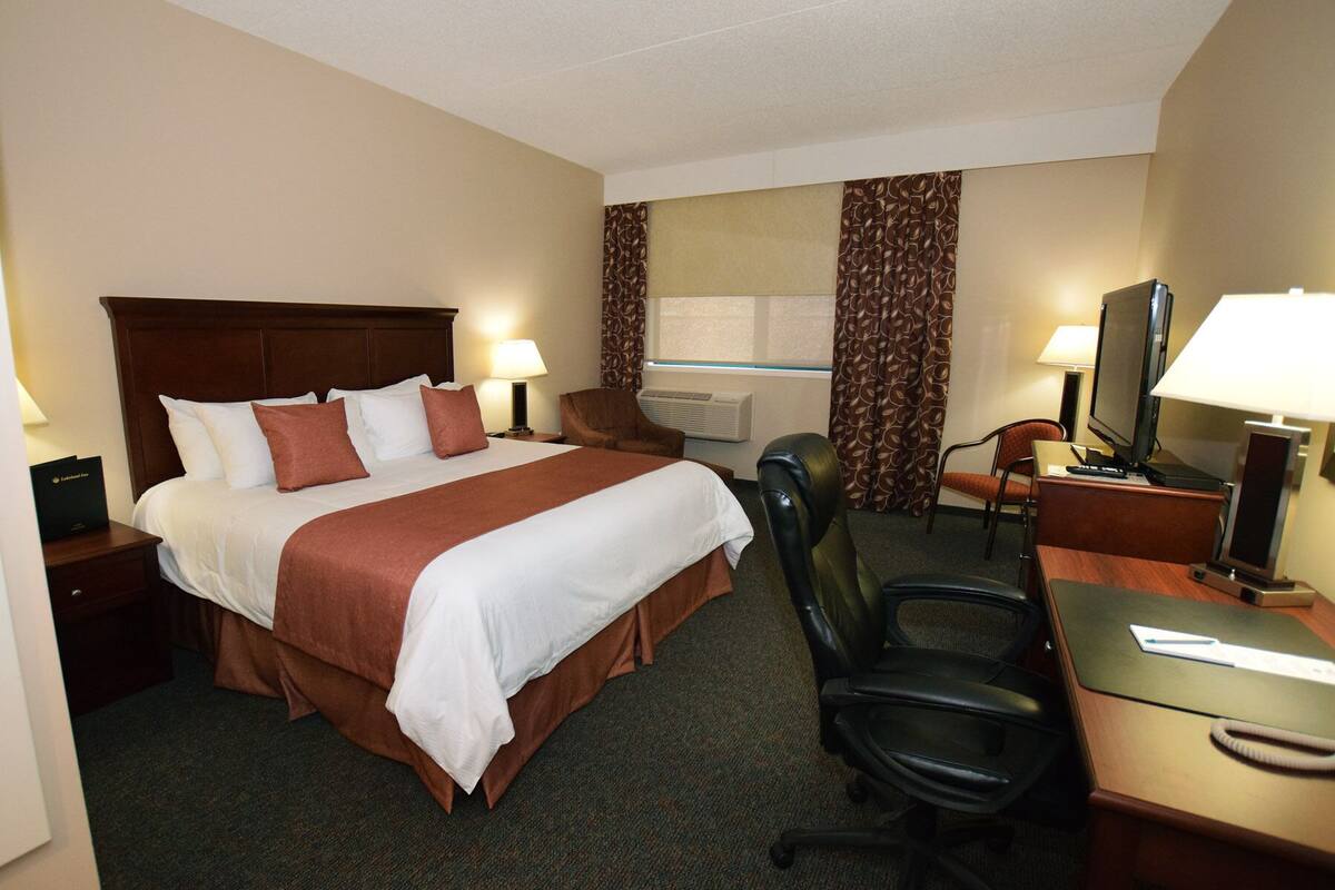 Une chambre d’hôtel avec un grand lit, un bureau avec une chaise, une télévision et une lampe de bureau.