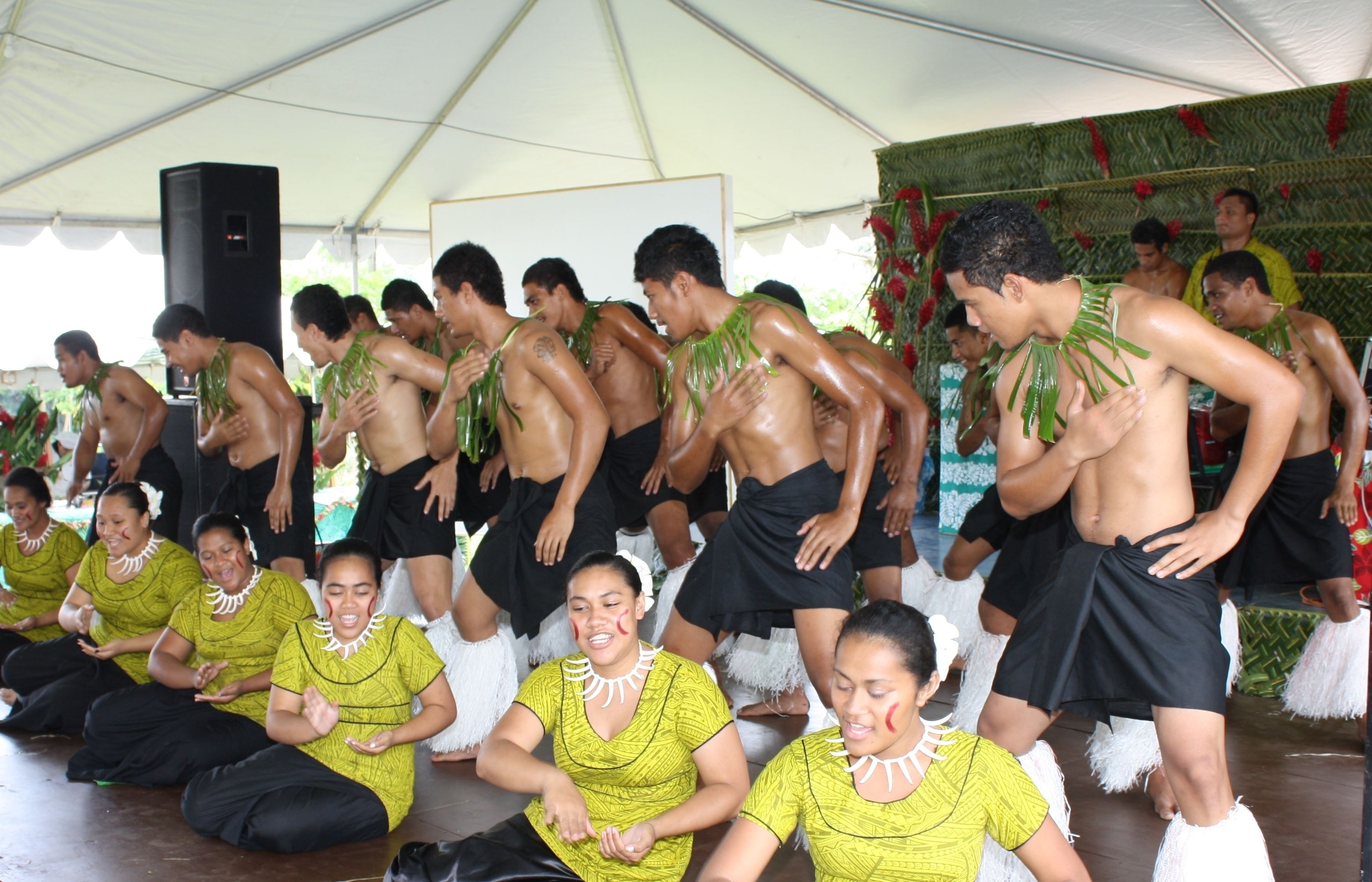 Un grupo de personas con vestimenta tradicional bailando bajo una carpa.