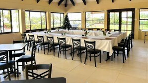 A conference room with a high ceiling and large windows, tables set for a meeting, and a Christmas tree. - Insel Fehmarn Hotel (Apia)