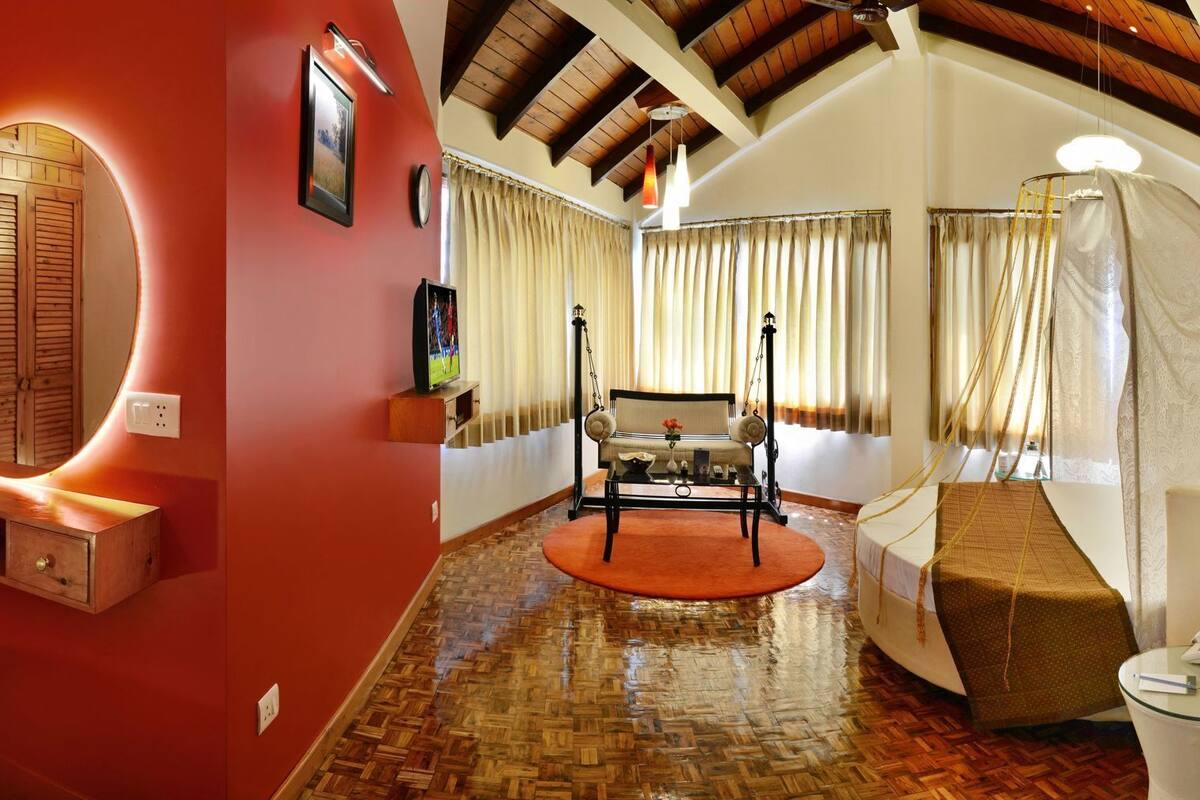 A room with a wooden bench, a small table, a hanging light fixture, and a bed with a canopy.