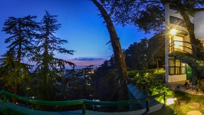 A modern building with a staircase and a view of trees and a sunset.
