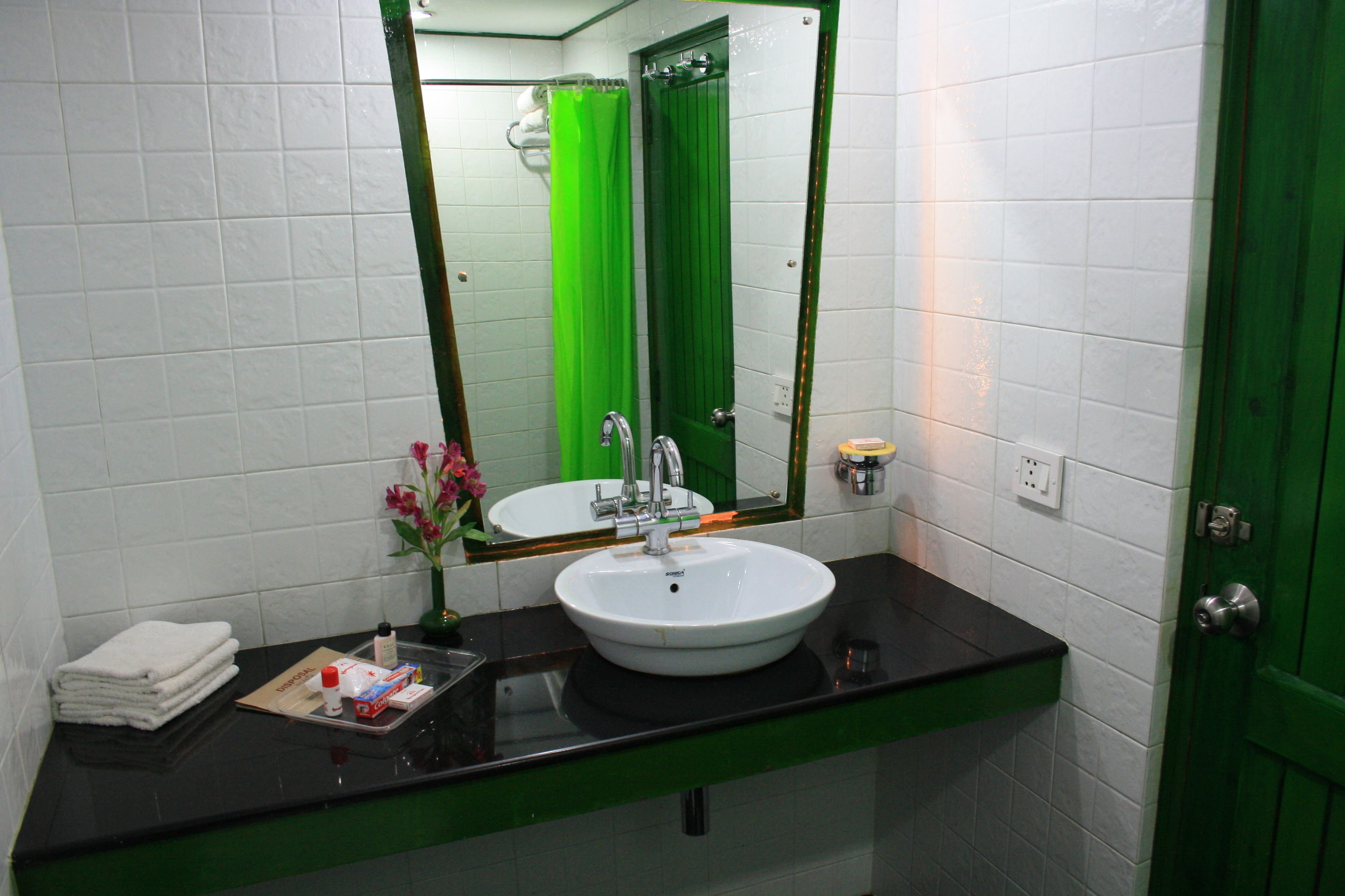 Een badkamer met een wit wastafelmeubel, een groen aanrechtblad en een groene deur.