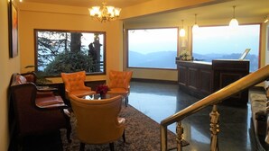 A spacious room with a large window offering a mountain view, a chandelier, and a dining area with a table and chairs.