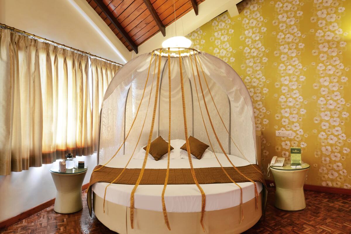 A circular bed with a canopy, two bedside tables, and a wall with a floral pattern.