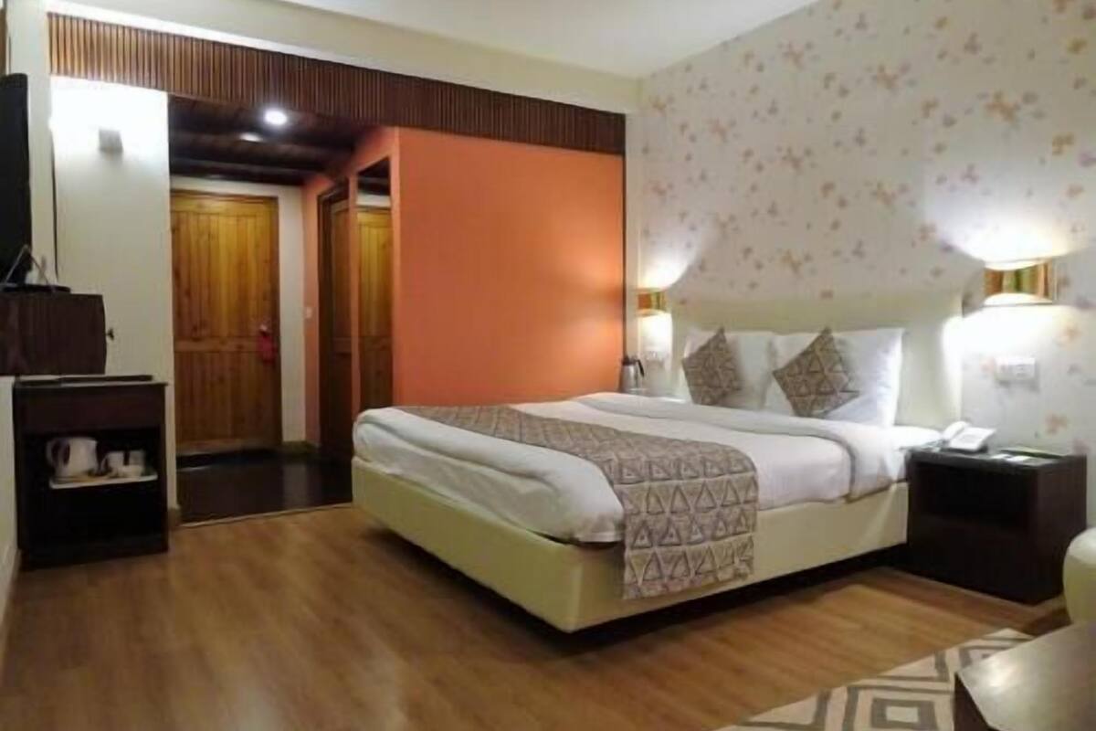 A hotel room with a bed, bedside tables, a wardrobe, and a door leading to another room.