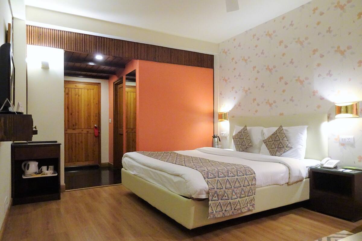 A hotel room with a bed, bedside tables, a wardrobe, and a bathroom visible through an open door.