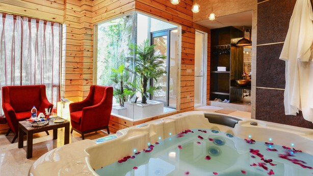 A spa room with a large bathtub, wooden walls, and a red chair.