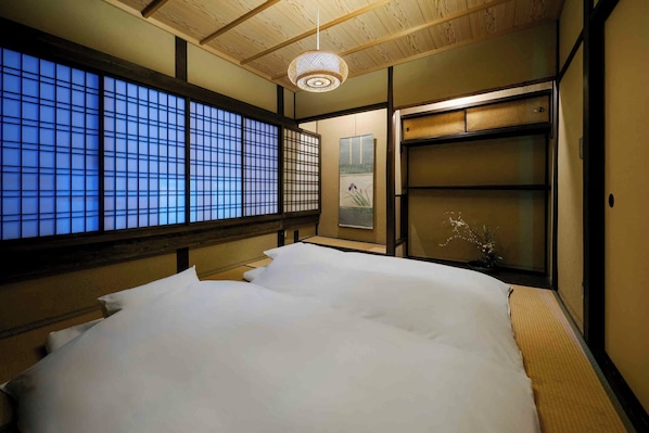 A traditional Japanese room with tatami flooring, a large shoji screen window, and a hanging lantern.