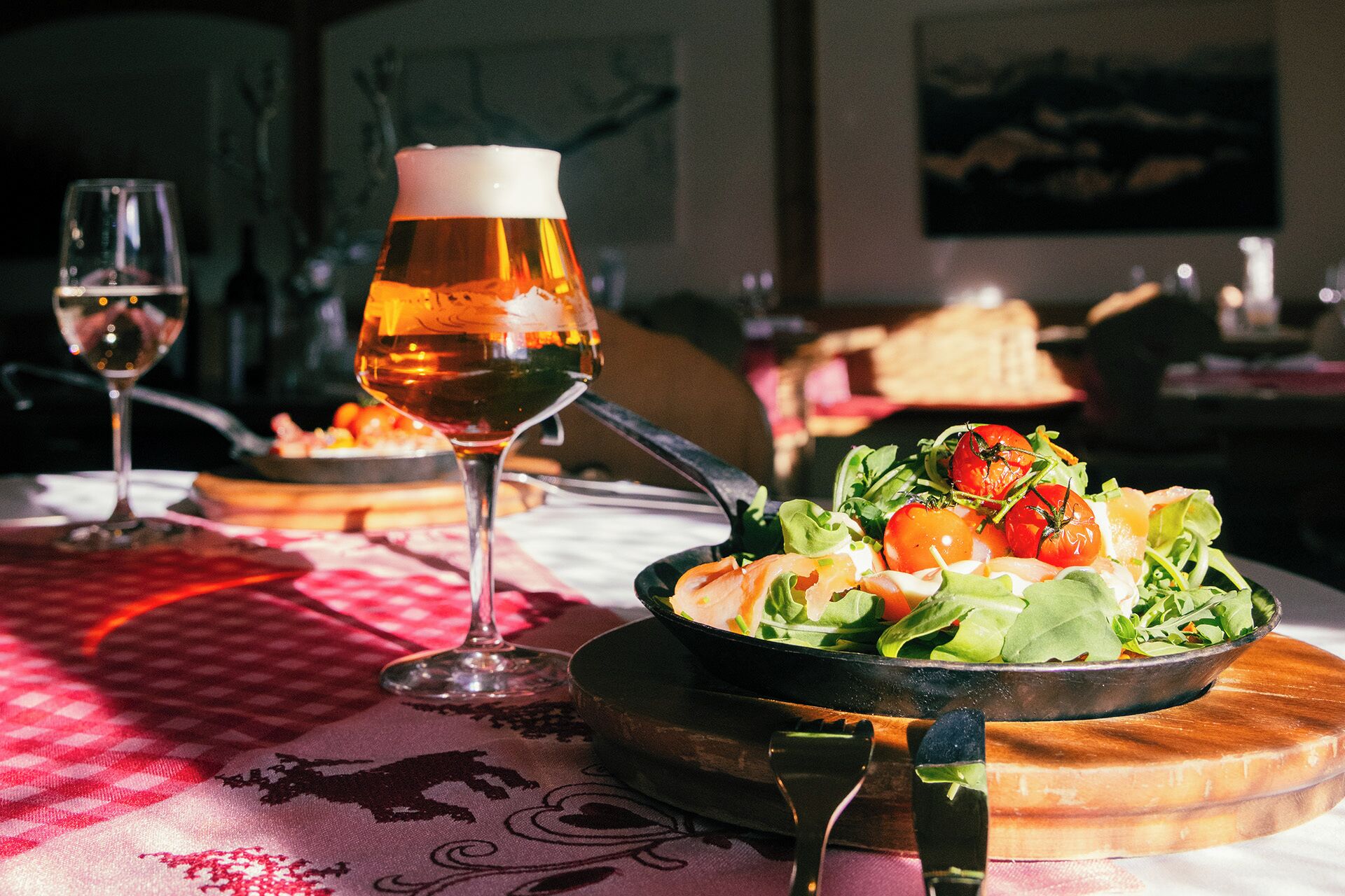 A dining table with a salad, a wine glass, and a beer glass.