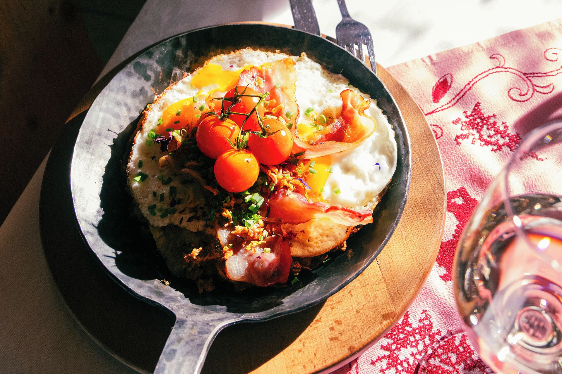 A skillet with a breakfast dish consisting of eggs, tomatoes, and bacon.