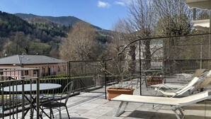 Una terraza en la azotea con vistas a la montaña, una mesa con sillas y sillones de relax.