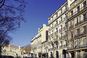 Uma fileira de edifícios clássicos em estilo europeu, com vários andares e varandas, sob um céu azul límpido.