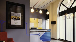 Uma receção com design moderno, um anúncio emoldurado na parede e uma grande janela que proporciona luz natural.