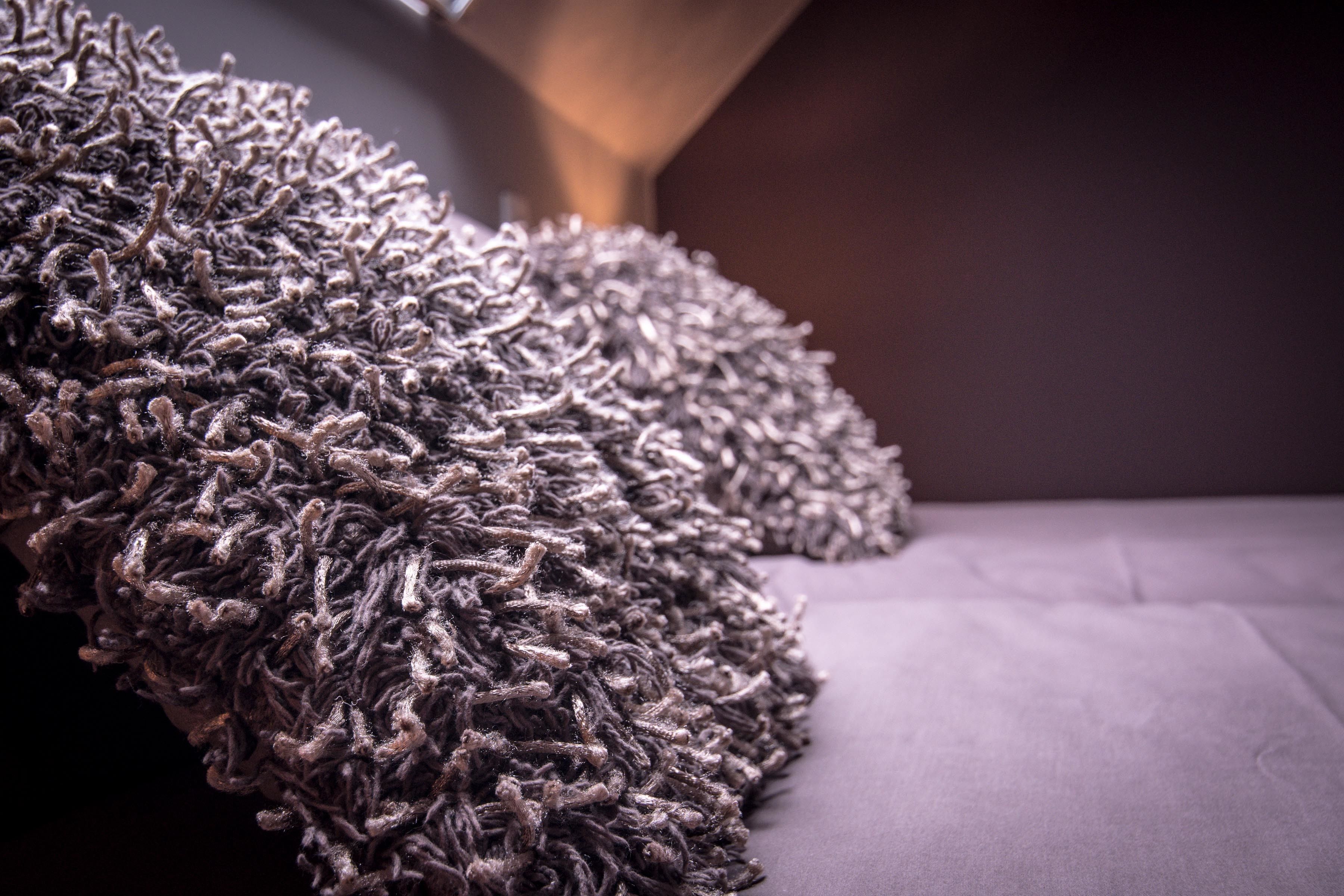 A close-up of a textured, dark-colored rug on a sofa.