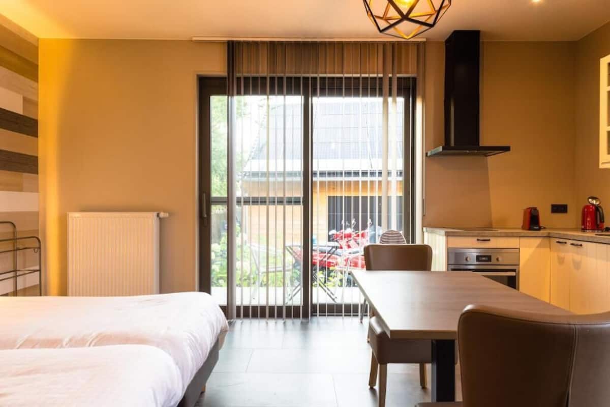 Une chambre d’hôtel avec deux lits, une table à manger, un coin cuisine et une vue sur l’extérieur.