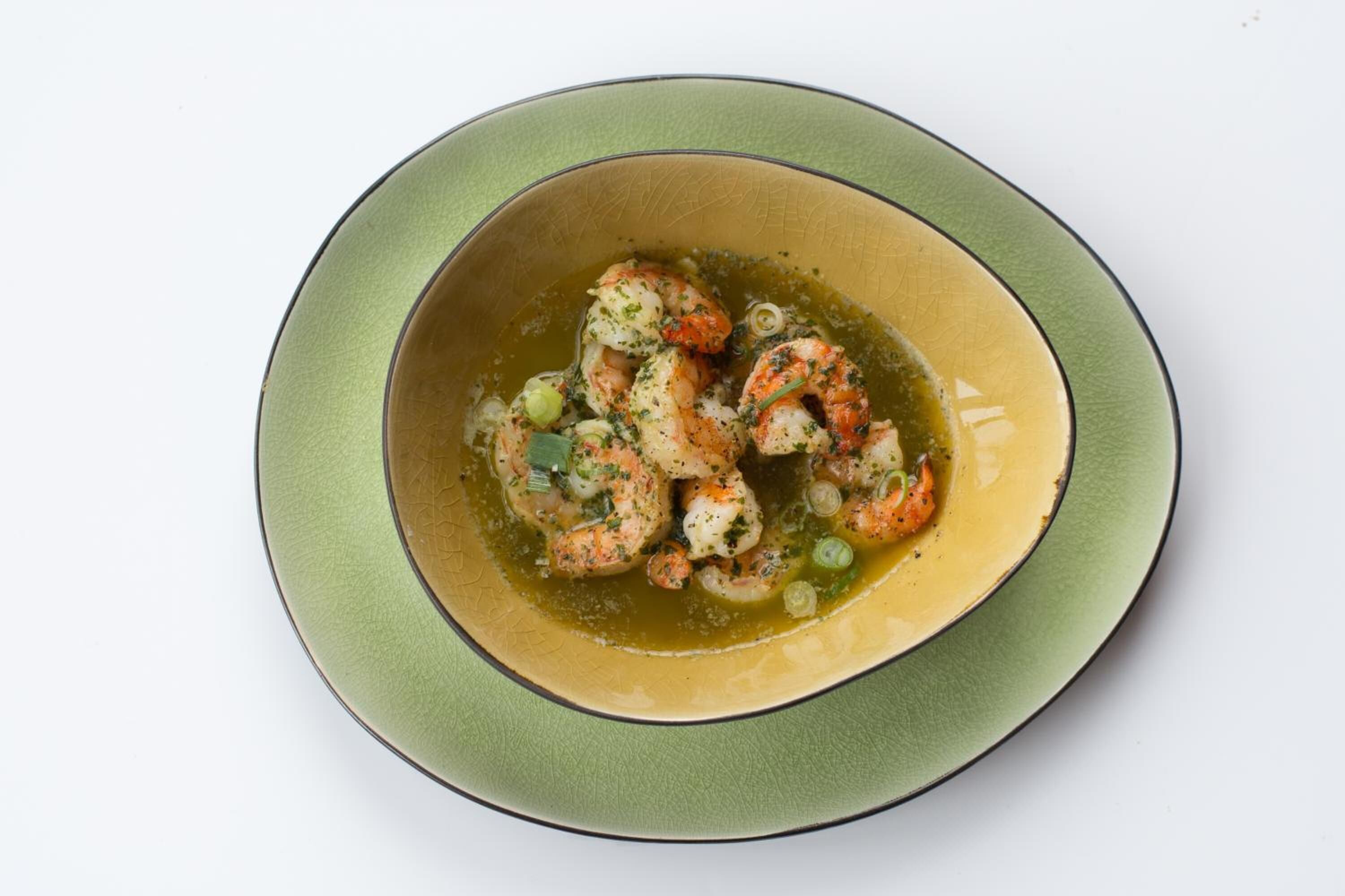 Un bol de crevettes dans un plat vert et beige.