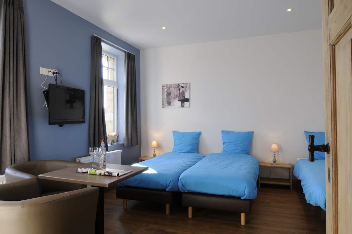 Une chambre d’hôtel moderne équipée de deux lits, d’un bureau, d’une chaise et d’un téléviseur.